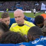 Chelsea team huddles around referee Paul Tierney ahead of Newcastle clash