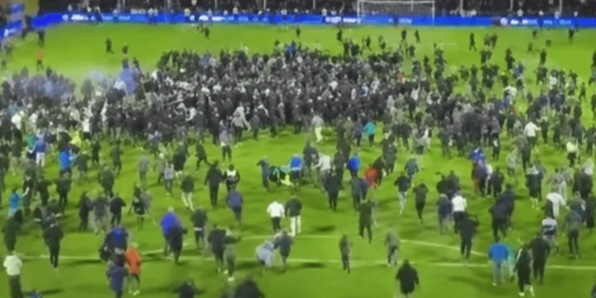 Filip Marschall tackled by fan during Stockport's play-off celebrations at Edgeley Park